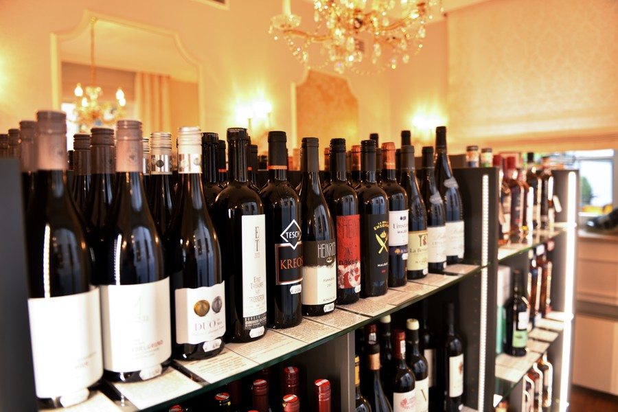 Nahaufnahme eines Weinregals mit verschiedenen Flaschen, teilweise mit minimalistischen Etiketten.