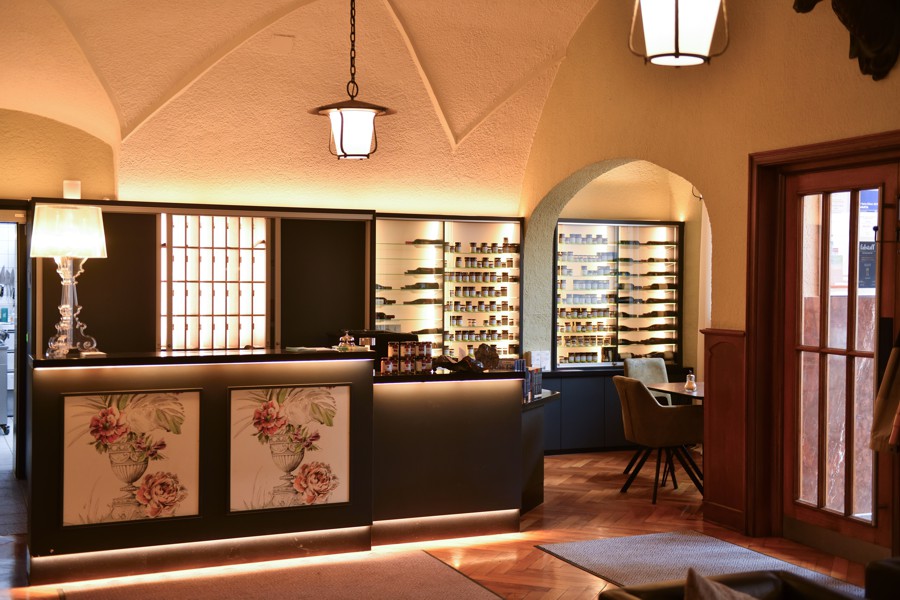 Thekenbereich in dunklem Holz mit beleuchtetem Rückregal, dekoriert mit floralen Elementen im asiatischen Stil.