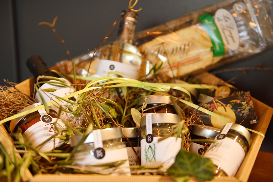 Geschenkkorb mit verschiedenen Feinkostprodukten, dekoriert mit Stroh und Naturmaterialien.