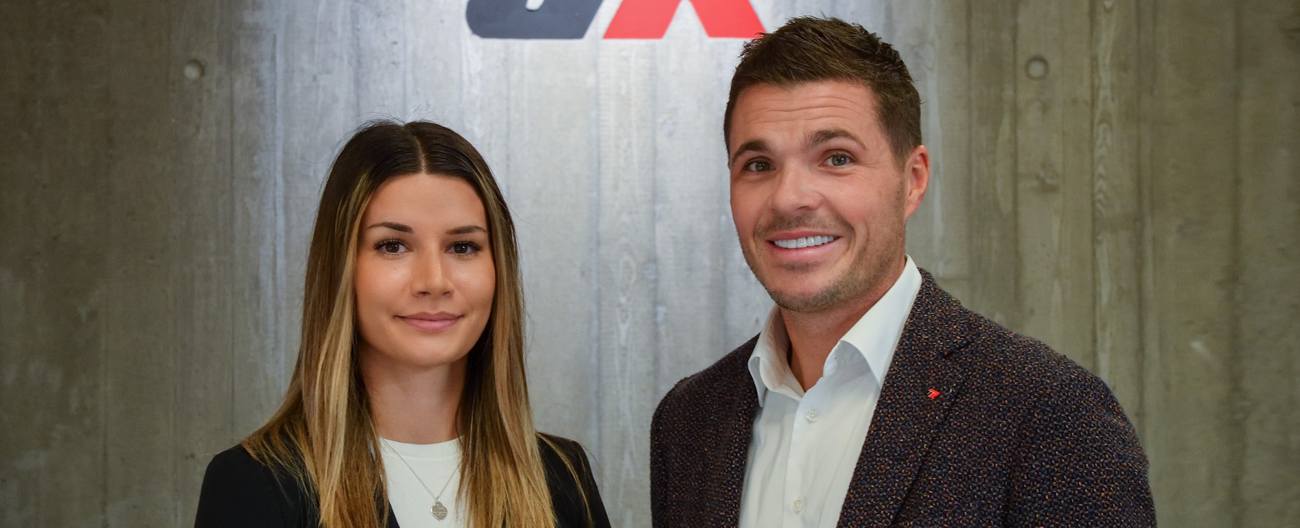 Sandra Hoffmann und Ulrich Reitenberger vor einer Betonwand lächeln in die Kamera