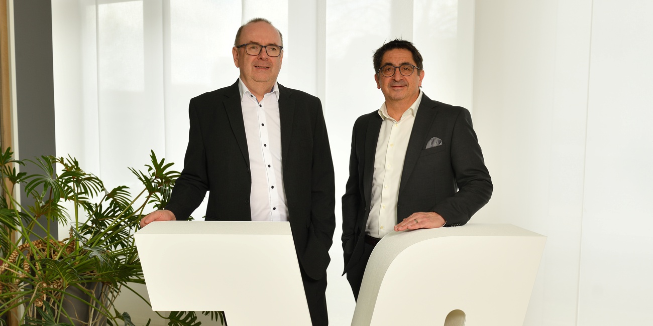 Alwin Renner und Ewald Gebauer stehen hinter einem Rednerpult in Form des VR-Logos.